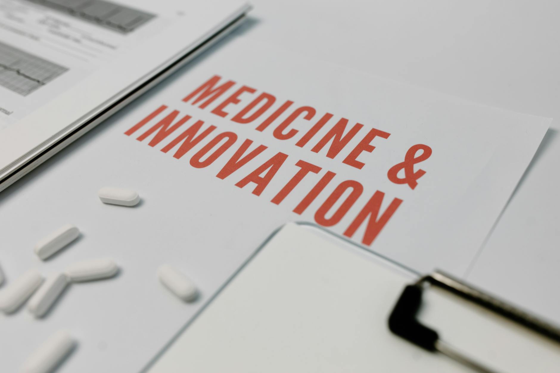 Close-up of 'Medicine & Innovation' paper with pills and documents on a desk.