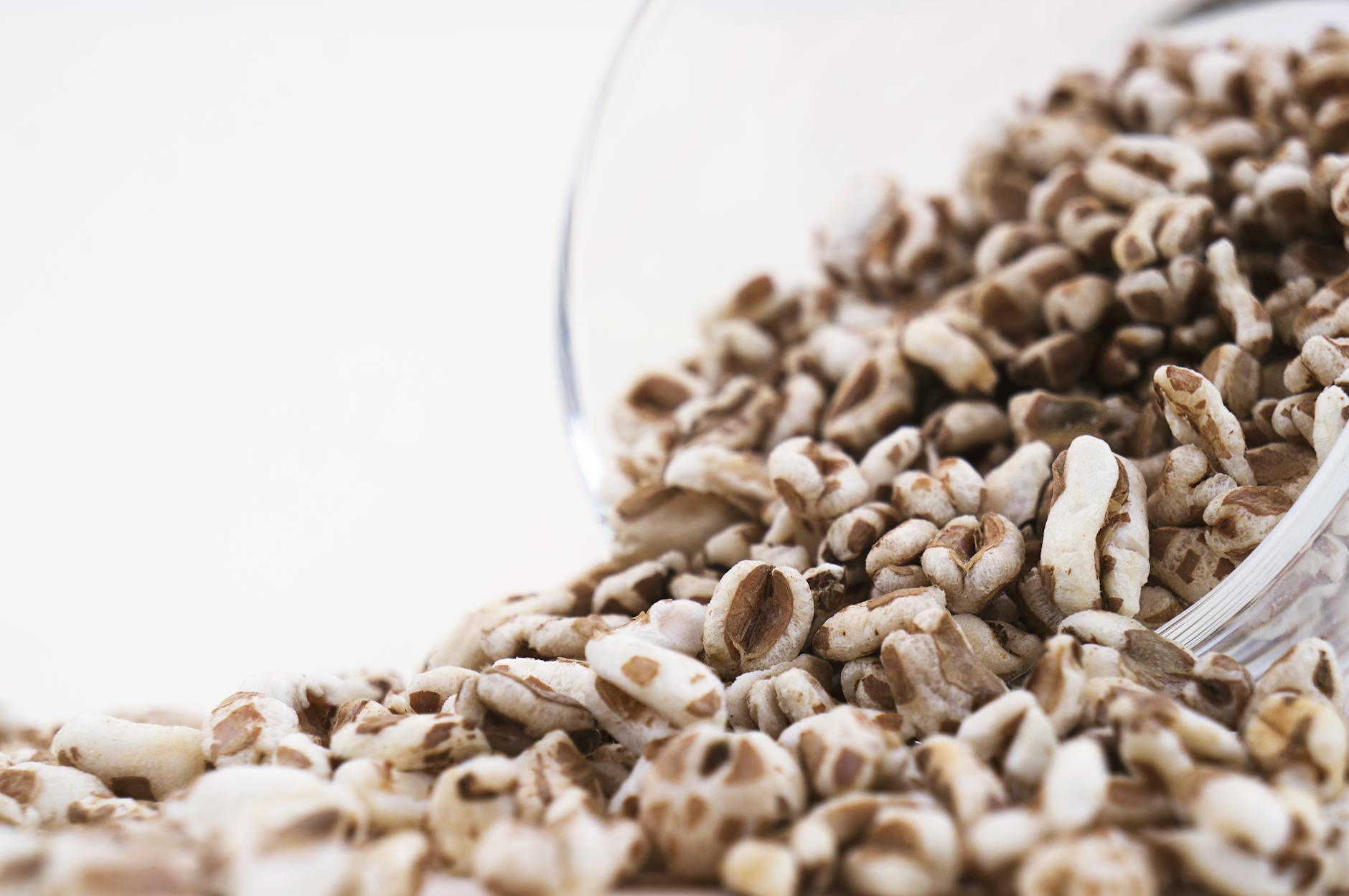High-resolution close-up of puffed cereal grains spilling from a glass bowl, perfect for healthy food concepts.